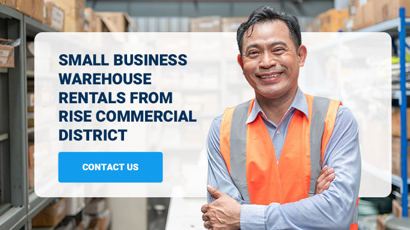 man smiling wearing orange vest with a small warehouse in the background