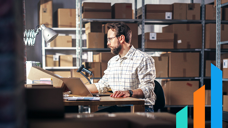 man sitting in a warehouse working on his computer at a desk