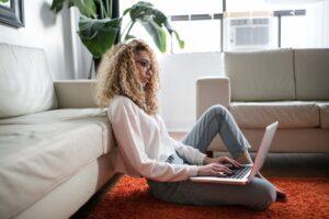 A woman sitting on the floor, using a laptop