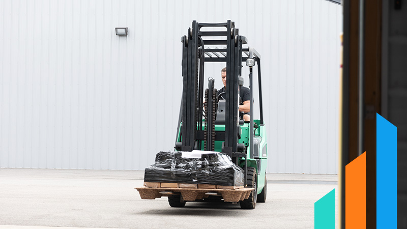 man driving a forklift with a pallet into a warehouse